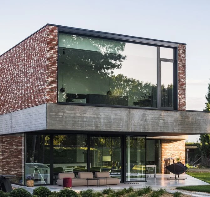 Maison contemporaine en brique avec fenêtres à cadres noirs — référence Reynaers.